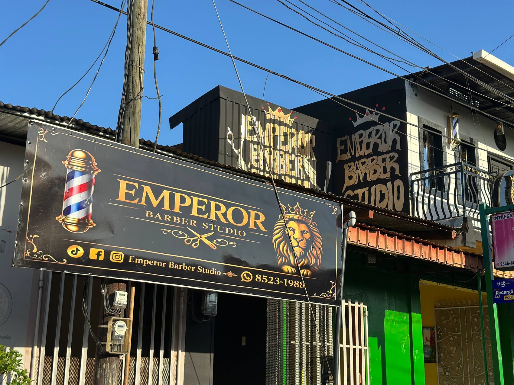 Fachada real de Emperor Barber Studio con r&oacute;tulo urbano y logo de le&oacute;n