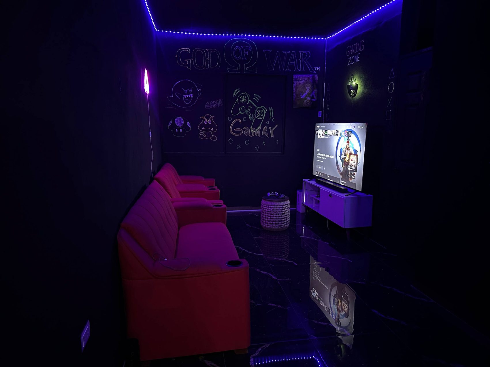 Sala de espera gamer con sillones rojos y pantalla en Emperor Barber Studio