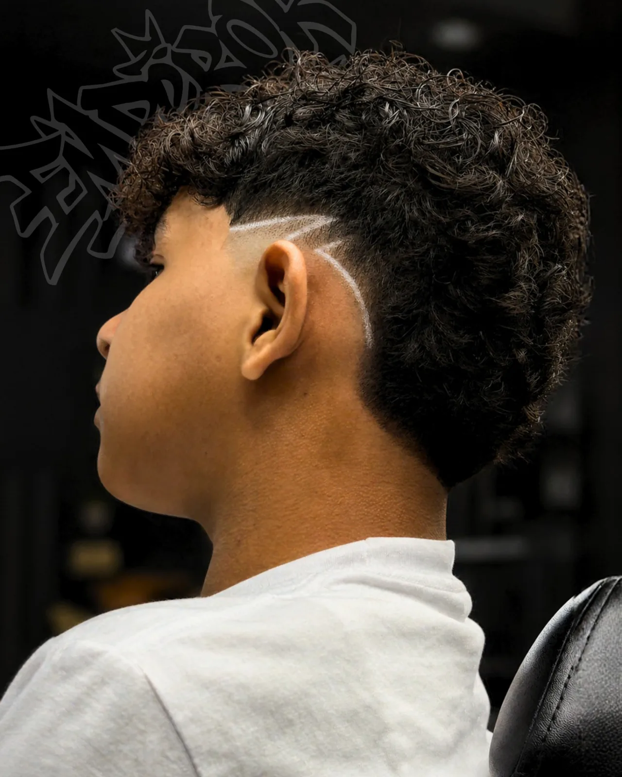 Corte con rizos arriba, degradado y diseño de líneas a navaja